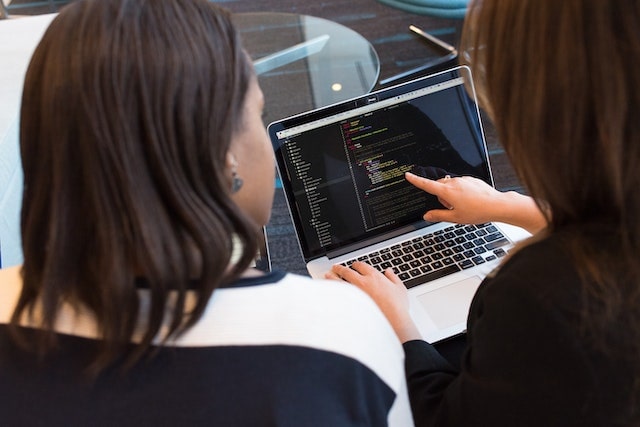 two people looking at code on laptop