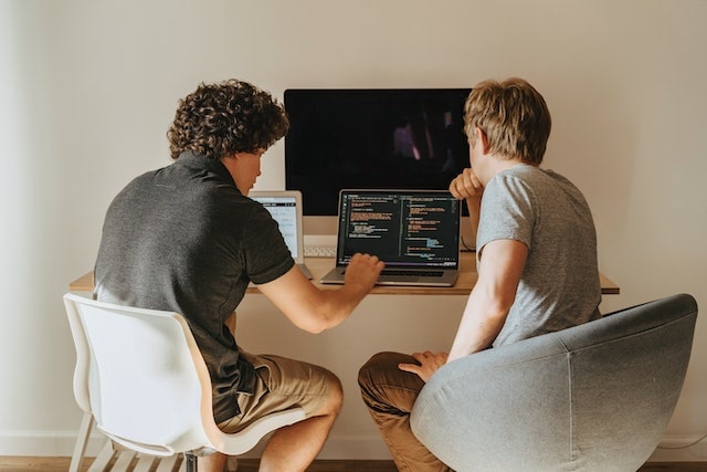 two people looking at code on a laptop